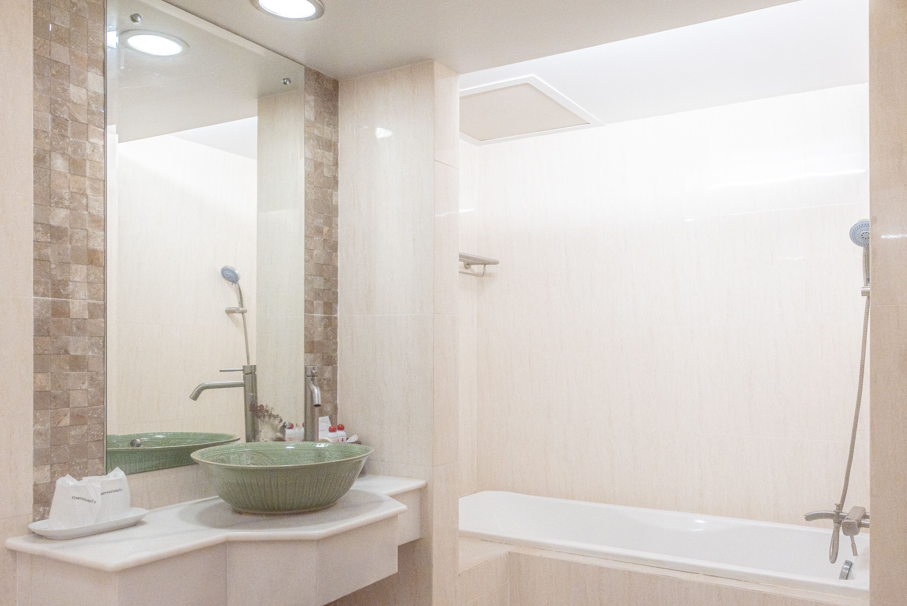 A bathroom with a large green sink, a mirror, and a bathtub.