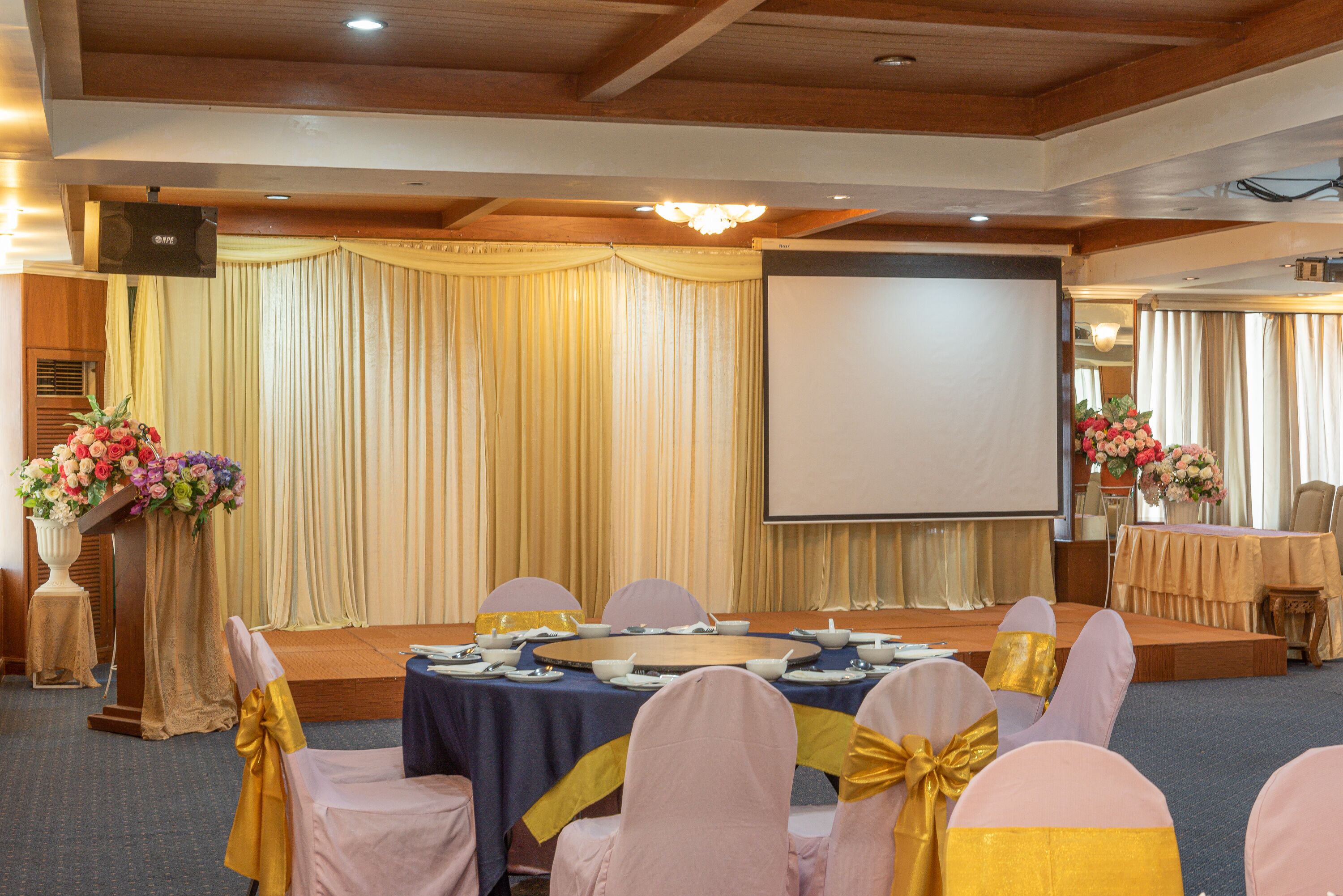 A conference room with a stage, a podium, and a screen.