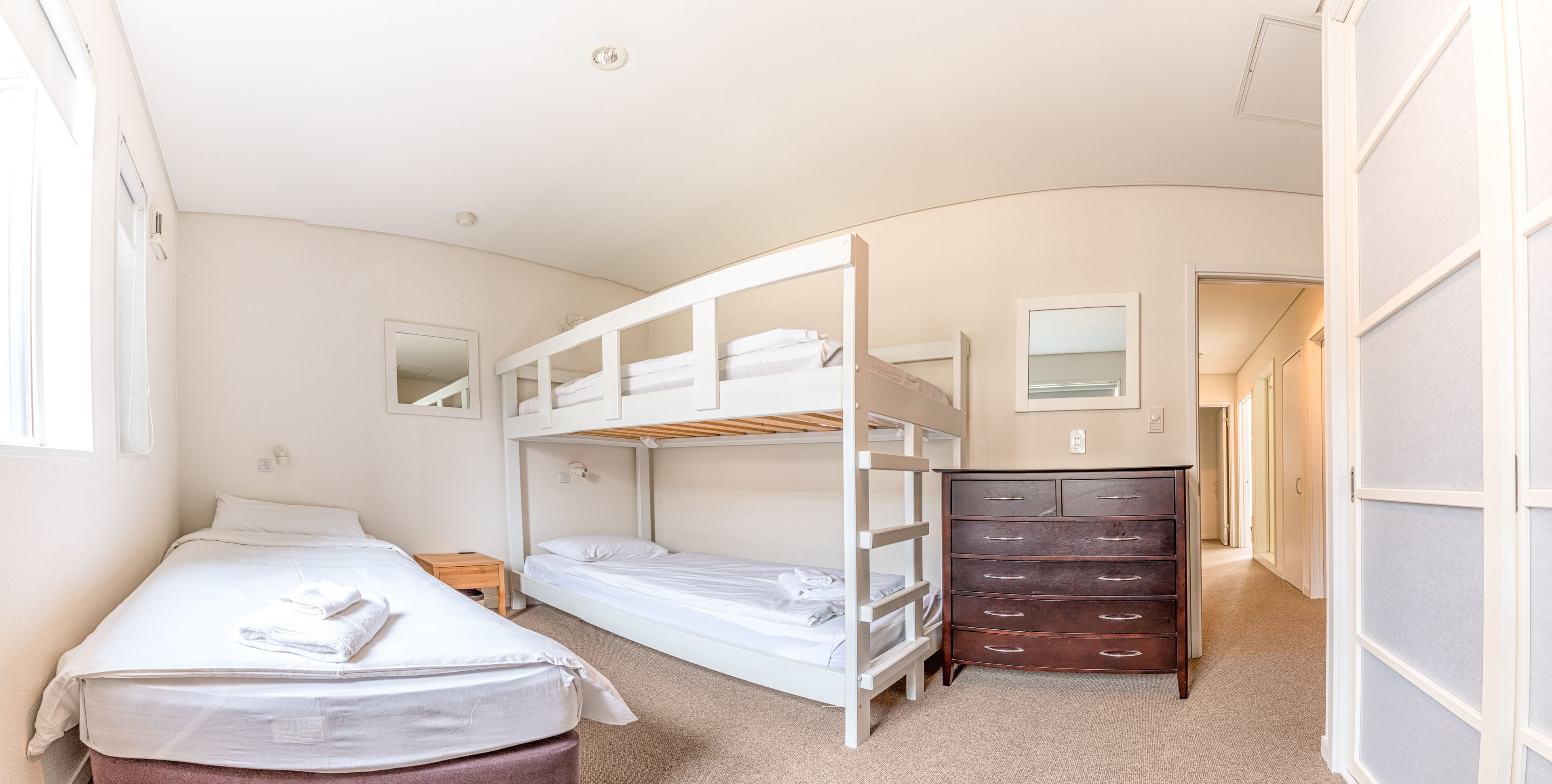 A bunk bed room with a dresser and a mirror.