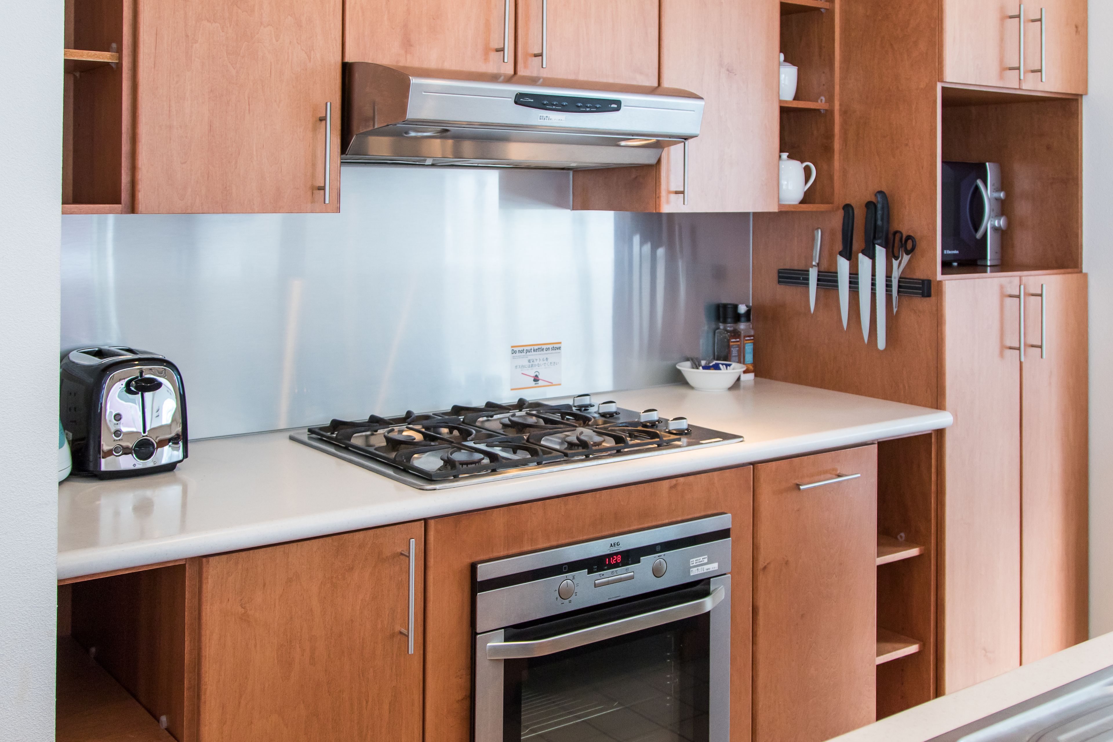 A kitchen with wooden cabinets, a stainless steel refrigerator, a gas stove, a toaster, and a built-in oven.