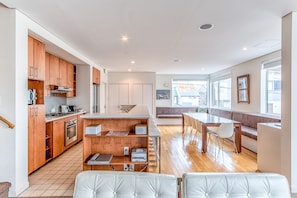 A modern kitchen with wooden cabinets, a dining area with a bench, and a view of the outside.