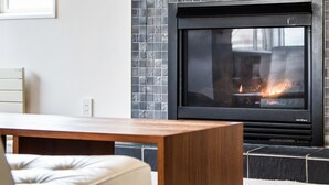 A modern living room with a fireplace, a wooden coffee table, and a sofa. - Wajima Niseko (Kutchan)