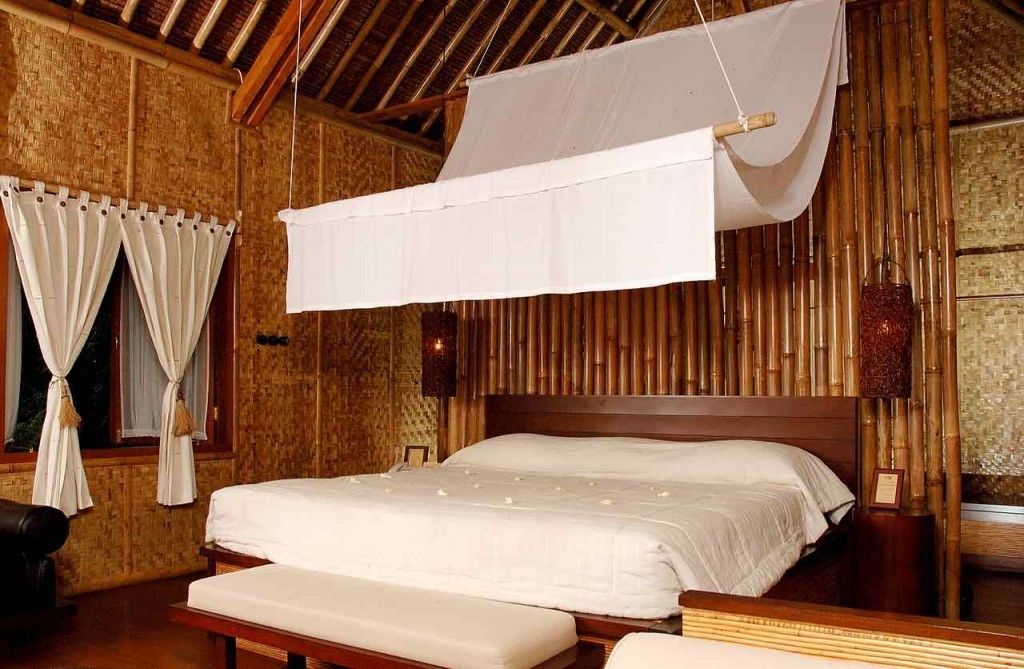 A room with a bed, a bench, and a hanging canopy.