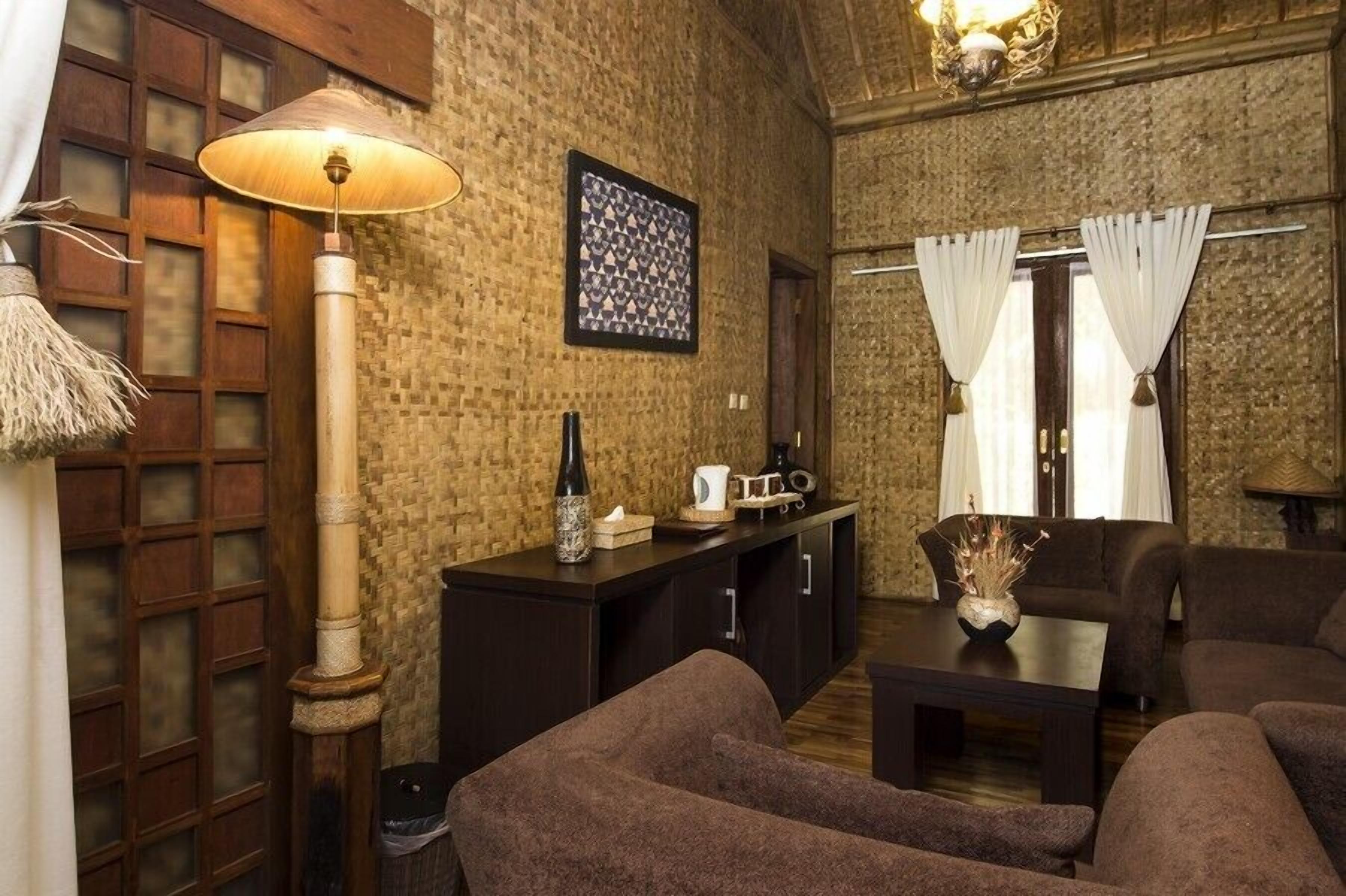 A cozy living room with a brick wall, a wooden cabinet, a sofa, a table, and a lamp.
