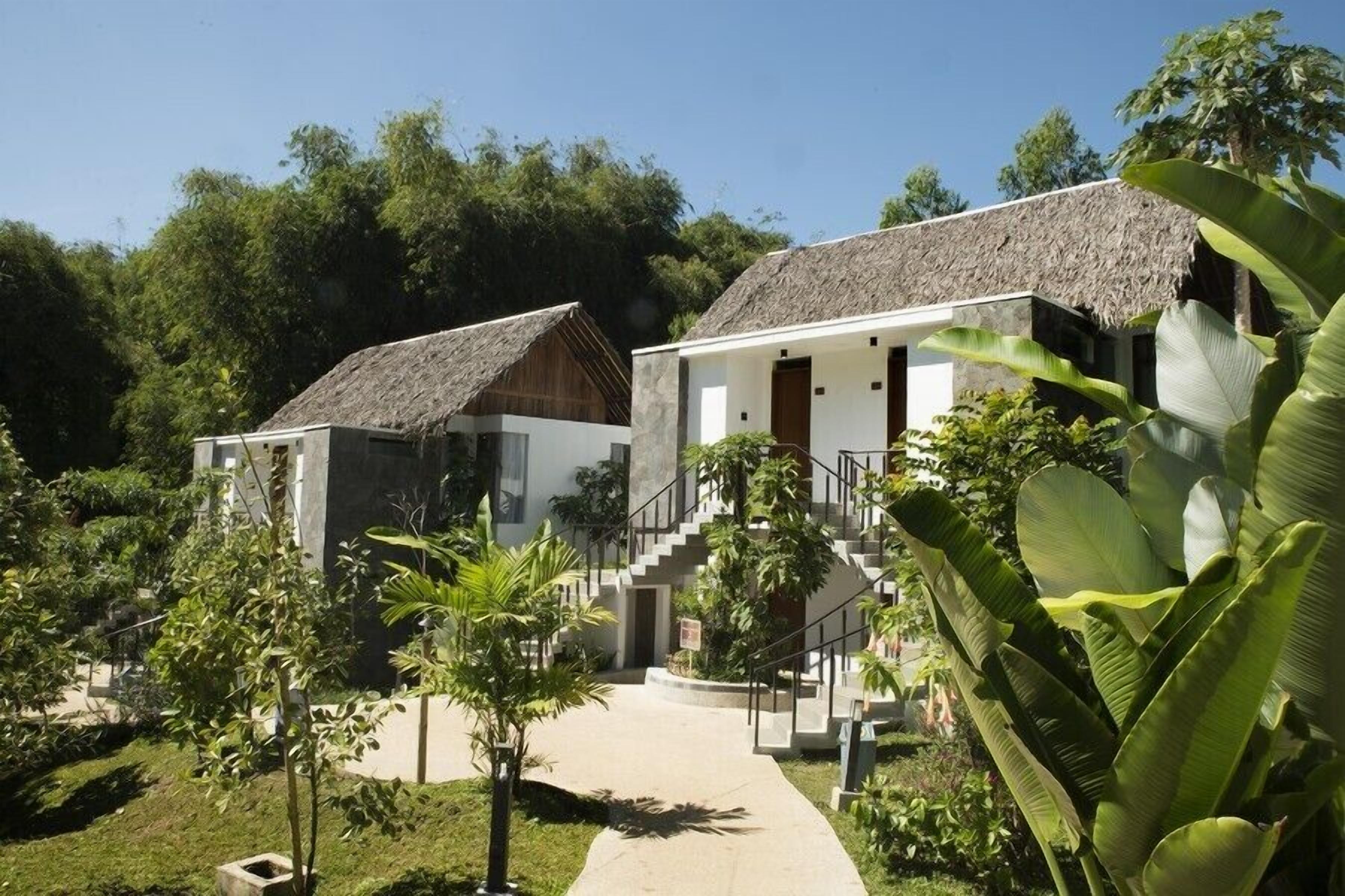A resort with two buildings, a central staircase, and lush greenery.