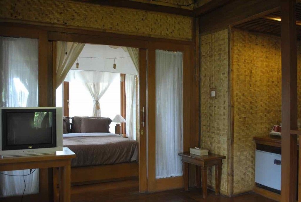 A bedroom with a bed, a television on a stand, a bedside table, and a small cabinet.