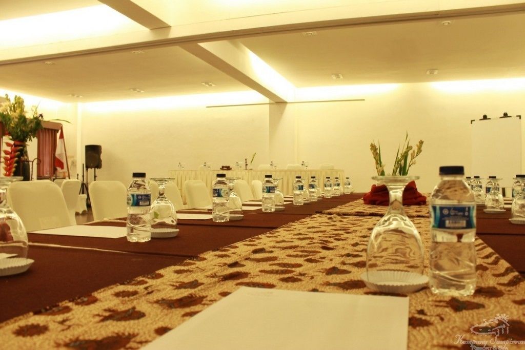 A conference room with a long table, chairs, water bottles, and a carpeted floor.