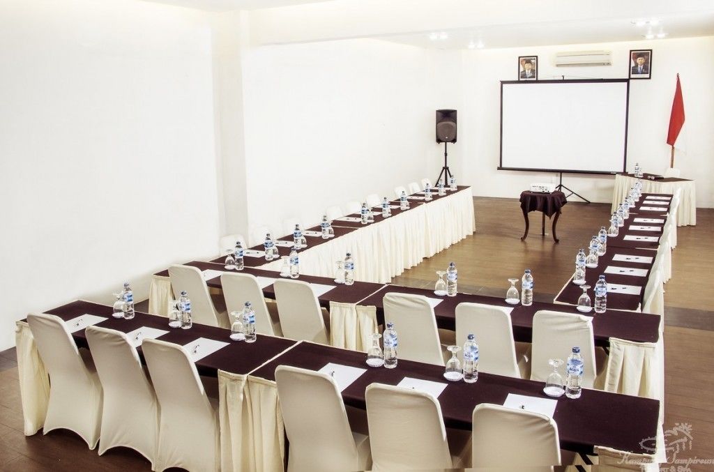 Un salón de conferencias con una larga mesa dispuesta para una reunión, equipado con sillas, botellas de agua y tarjetas de identificación.