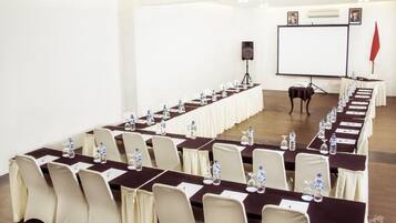 Un salón de conferencias con una larga mesa dispuesta para una reunión, equipado con sillas, botellas de agua y tarjetas de identificación.
