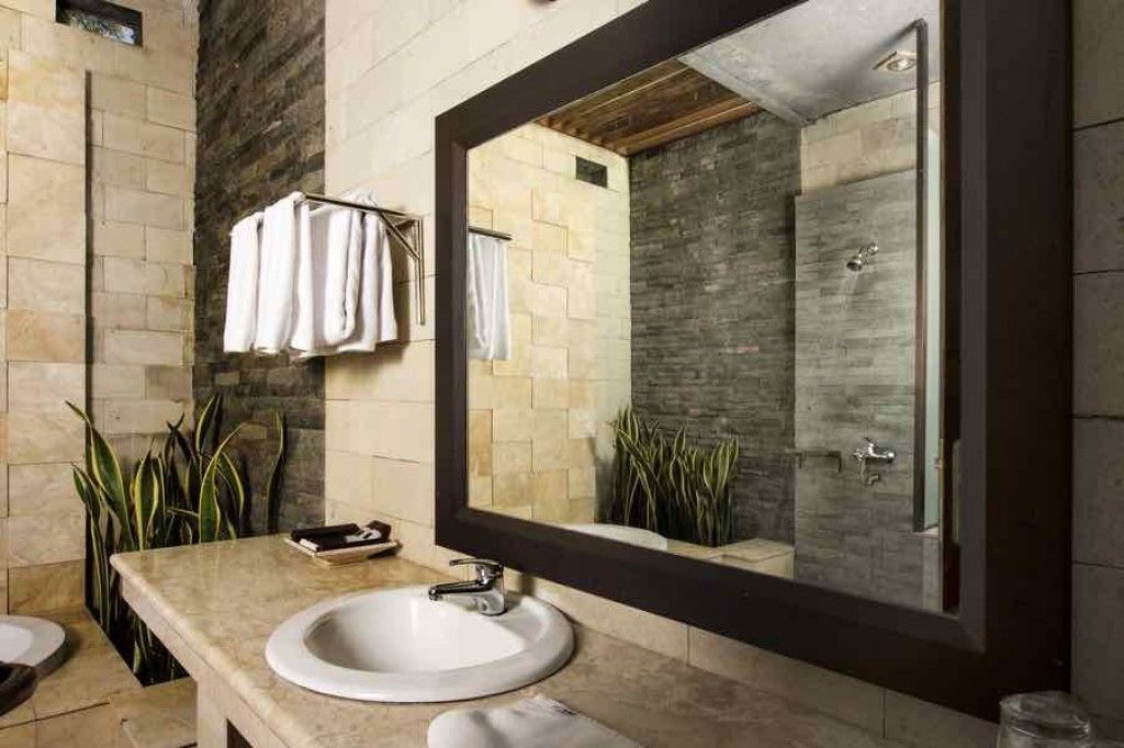 A bathroom with a large mirror, a sink, and a shower area.