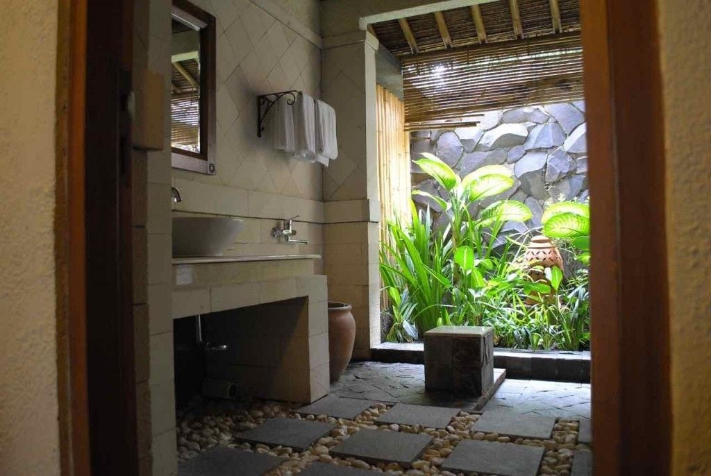 Un baño con suelo de baldosas de piedra, un lavabo y un espejo.