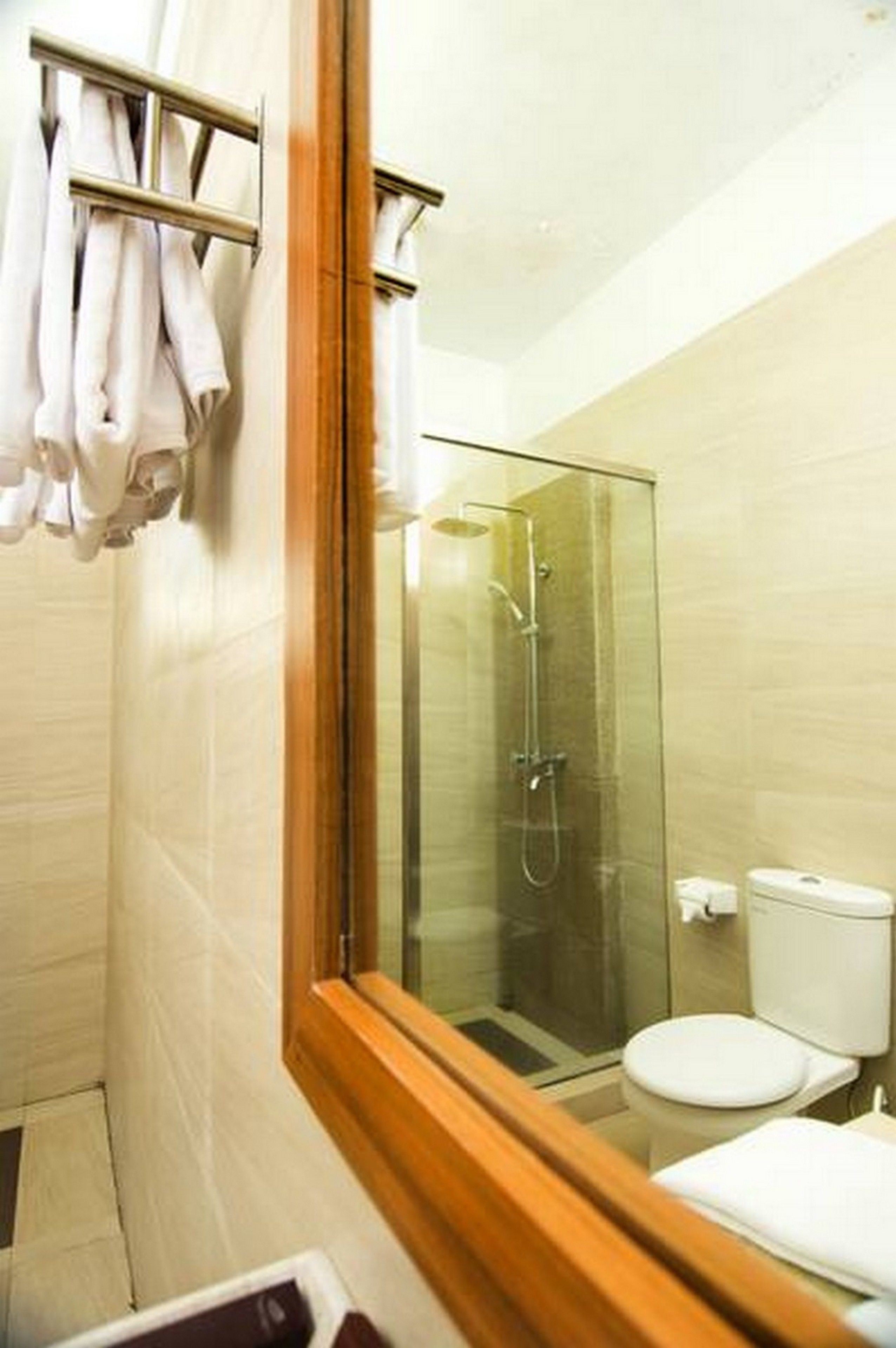 Casa de banho moderna com chuveiro em cabine de vidro, sanita branca e toalheiro com toalhas brancas.