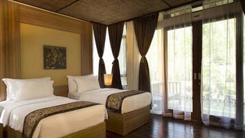 Habitación de hotel con dos camas, un ventanal con cortinas, un ventilador de techo y un cuadro en la pared.