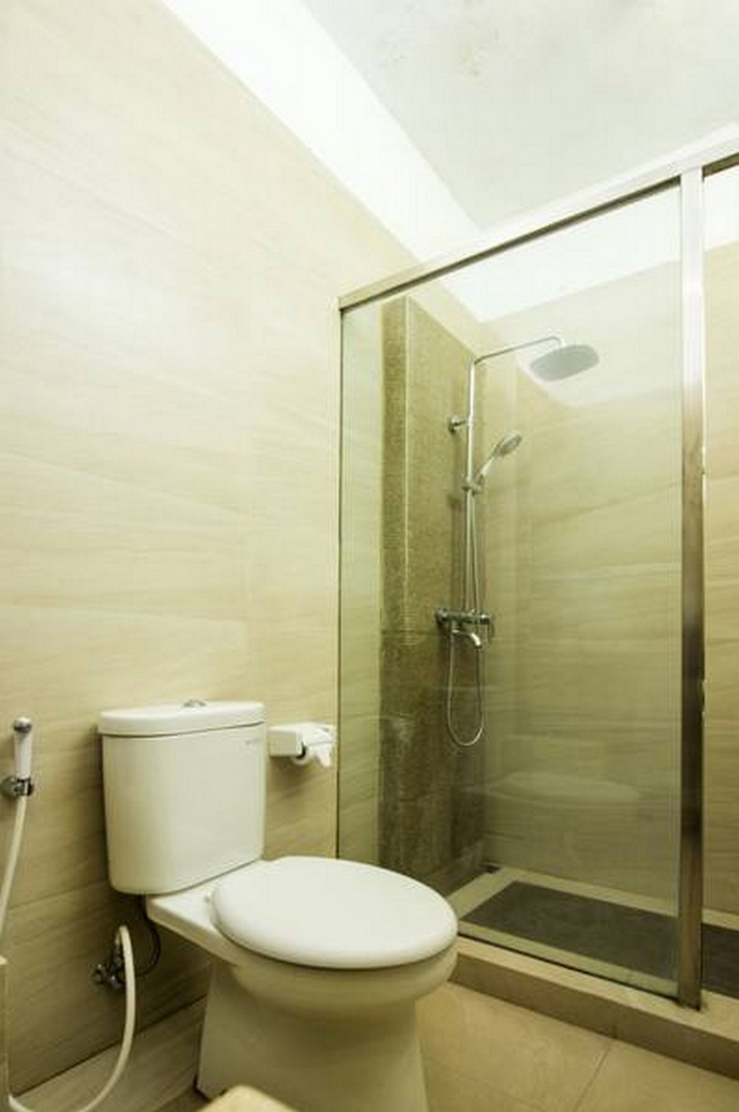 A bathroom with a toilet, a glass-enclosed shower, and a tiled floor.