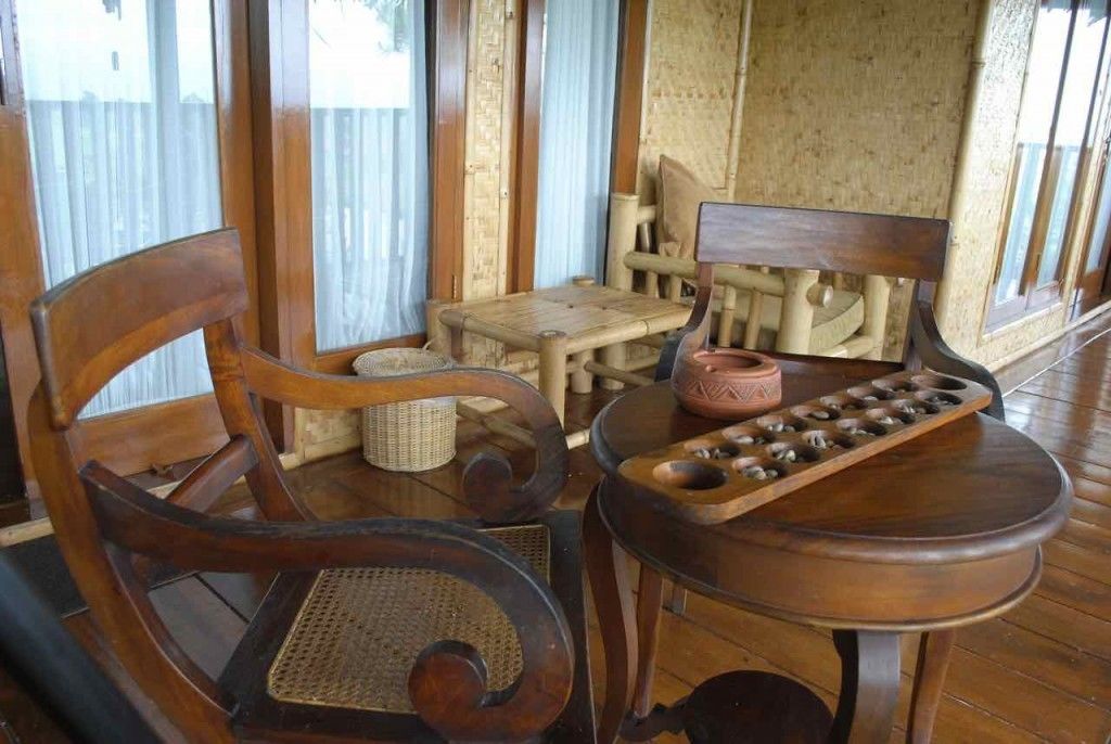 A wooden room with a woven chair, a small table with a woven basket, and a wooden bench.