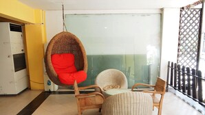 A seating area with wicker furniture and a red chair. - The Boss's Place (Bangkok)