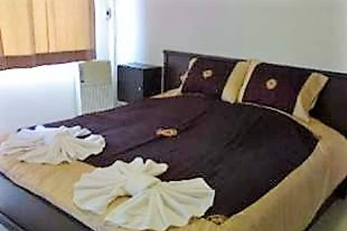 A neatly made bed with a dark headboard, white pillows, and a brown bedspread.