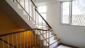 A staircase with wooden railings and white walls, leading to an upper floor. - The Boss's Place (Bangkok)