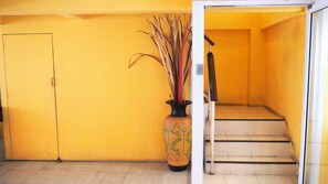 Un muro giallo con una porta e una scala che conduce a un piano superiore.