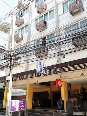 A multi-story building with balconies and a signboard for 'The Boss's Place' hotel.