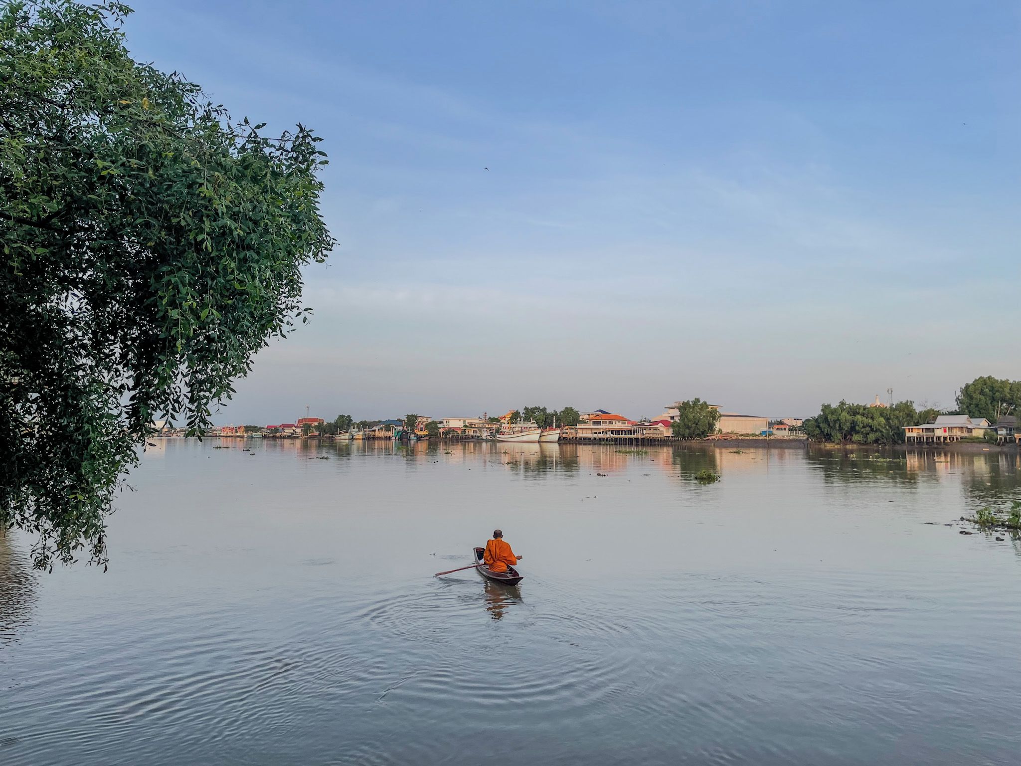 A calm body of water with a person in a boat, surrounded by buildings and trees.
