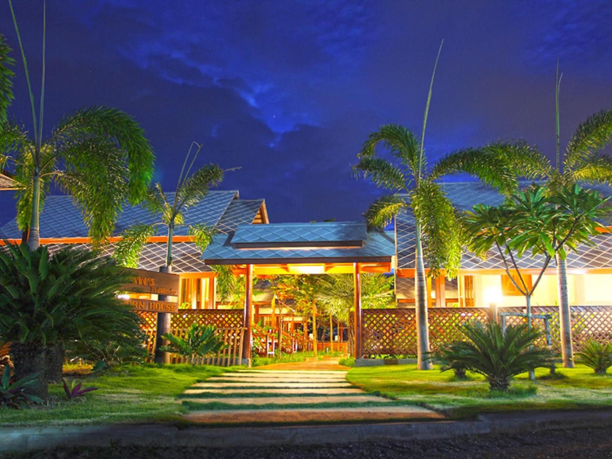 A hotel with a covered entrance, palm trees, and a well-lit pathway leading to the building.