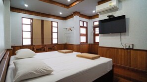Habitación de hotel con una cama grande, paneles de madera, un televisor de pantalla plana y un ventanal con vistas.
