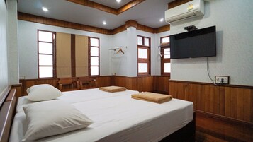 Habitación de hotel con una cama grande, paneles de madera, un televisor de pantalla plana y un ventanal con vistas.