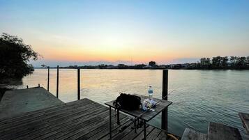 A wooden dock extending into calm water with a sunset in the background.