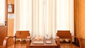 Una habitación con dos sillas de madera, una mesa con toallas y un vaso, y una puerta con un cartel.