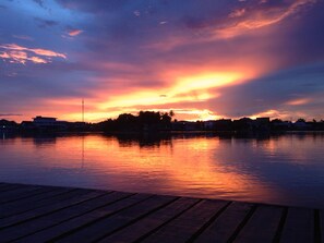 Un atardecer sobre un cuerpo de agua tranquilo con un muelle de madera al frente.
