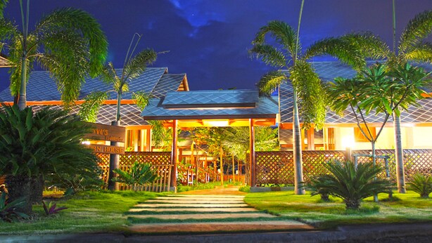 Un hotel con entrada cubierta, palmeras y un césped bien cuidado.