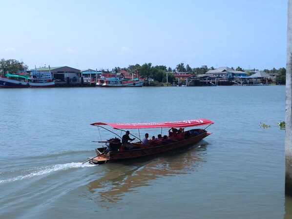 A boat with a red canopy and passengers, moving on a calm body of water.