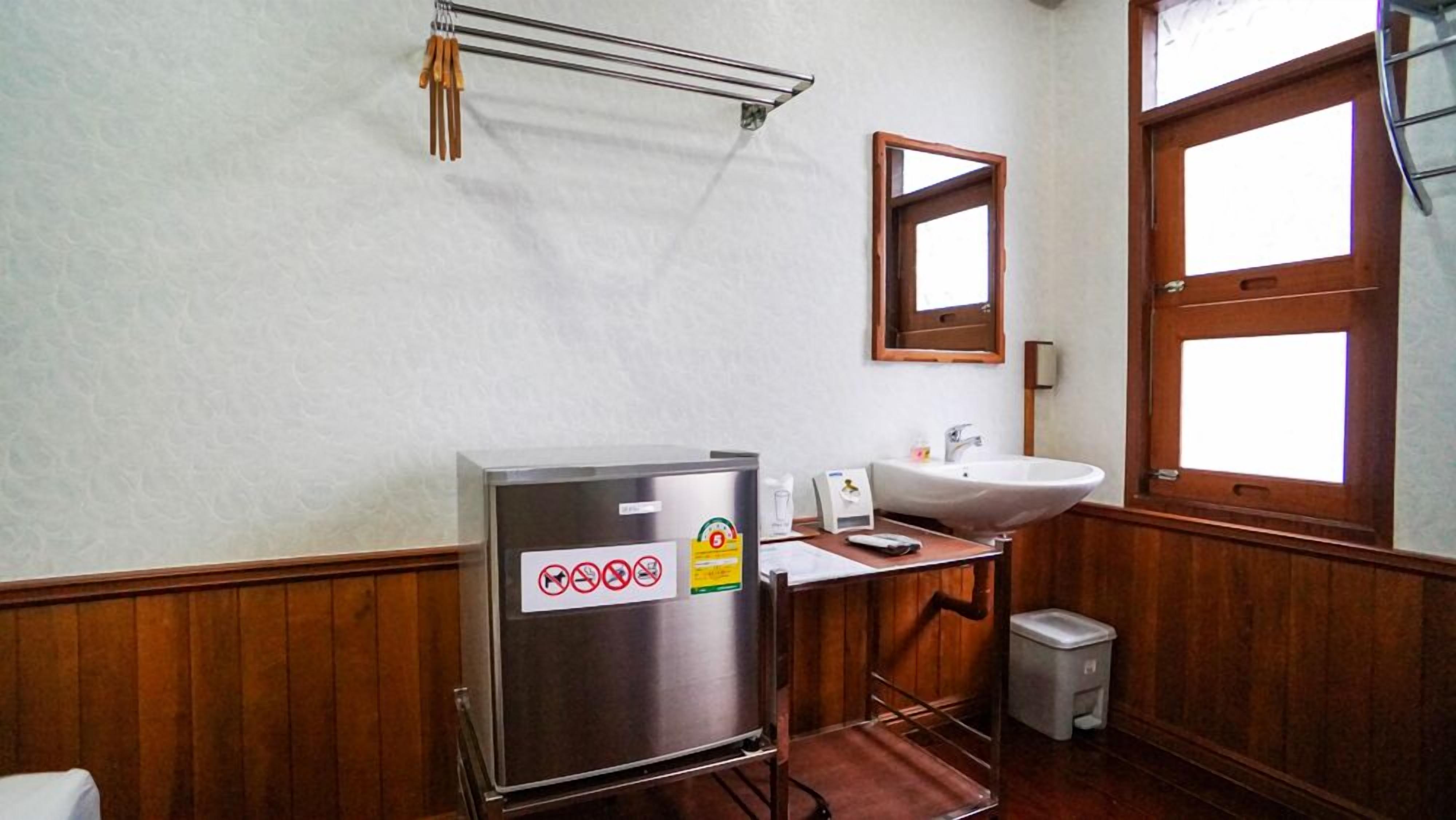 A bathroom with a sink, mirror, and a trash bin.
