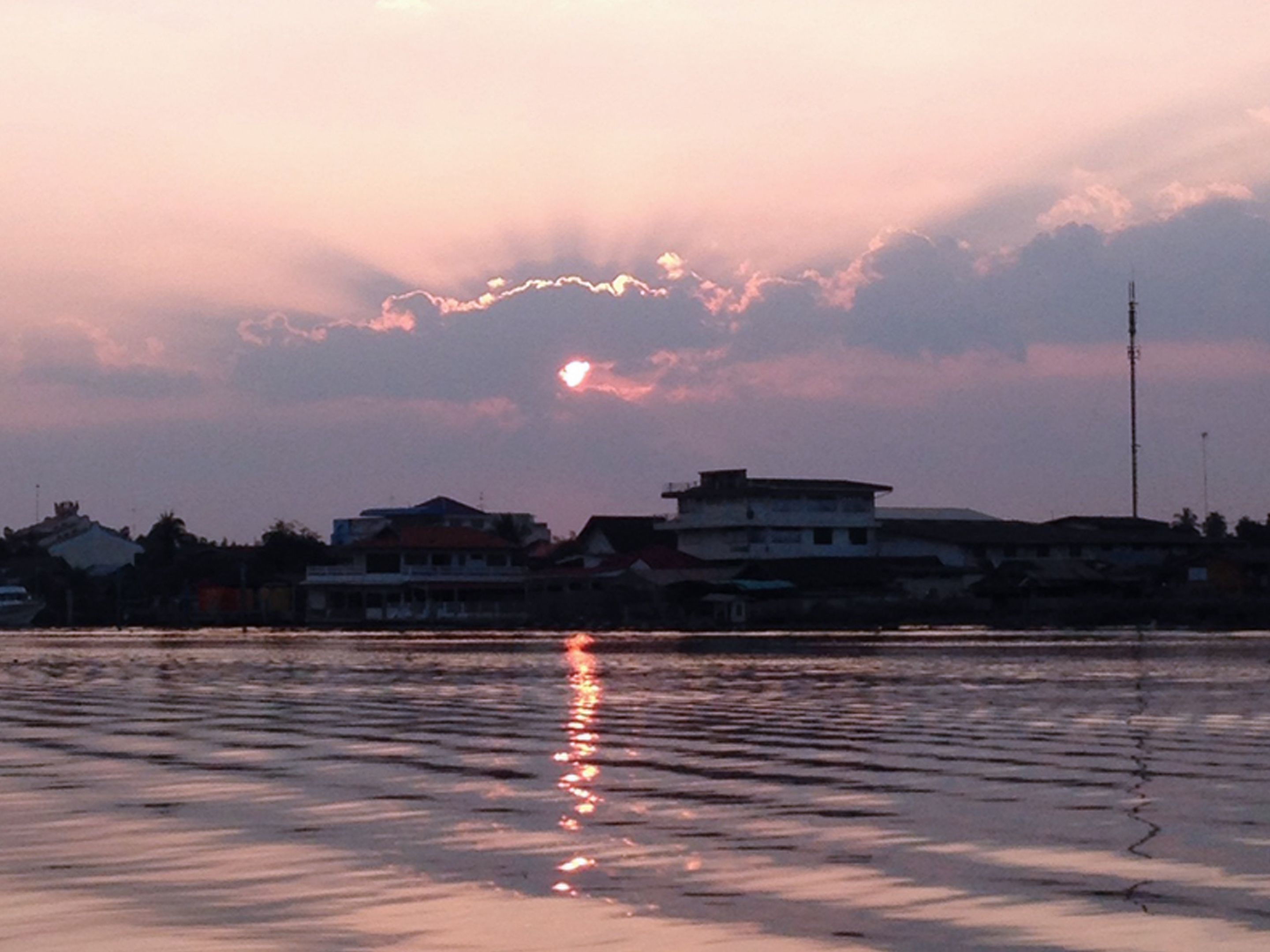 A sunset over a body of water with buildings in the background.