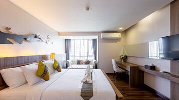 A hotel room with a large bed, a desk, a TV, and a window with curtains.