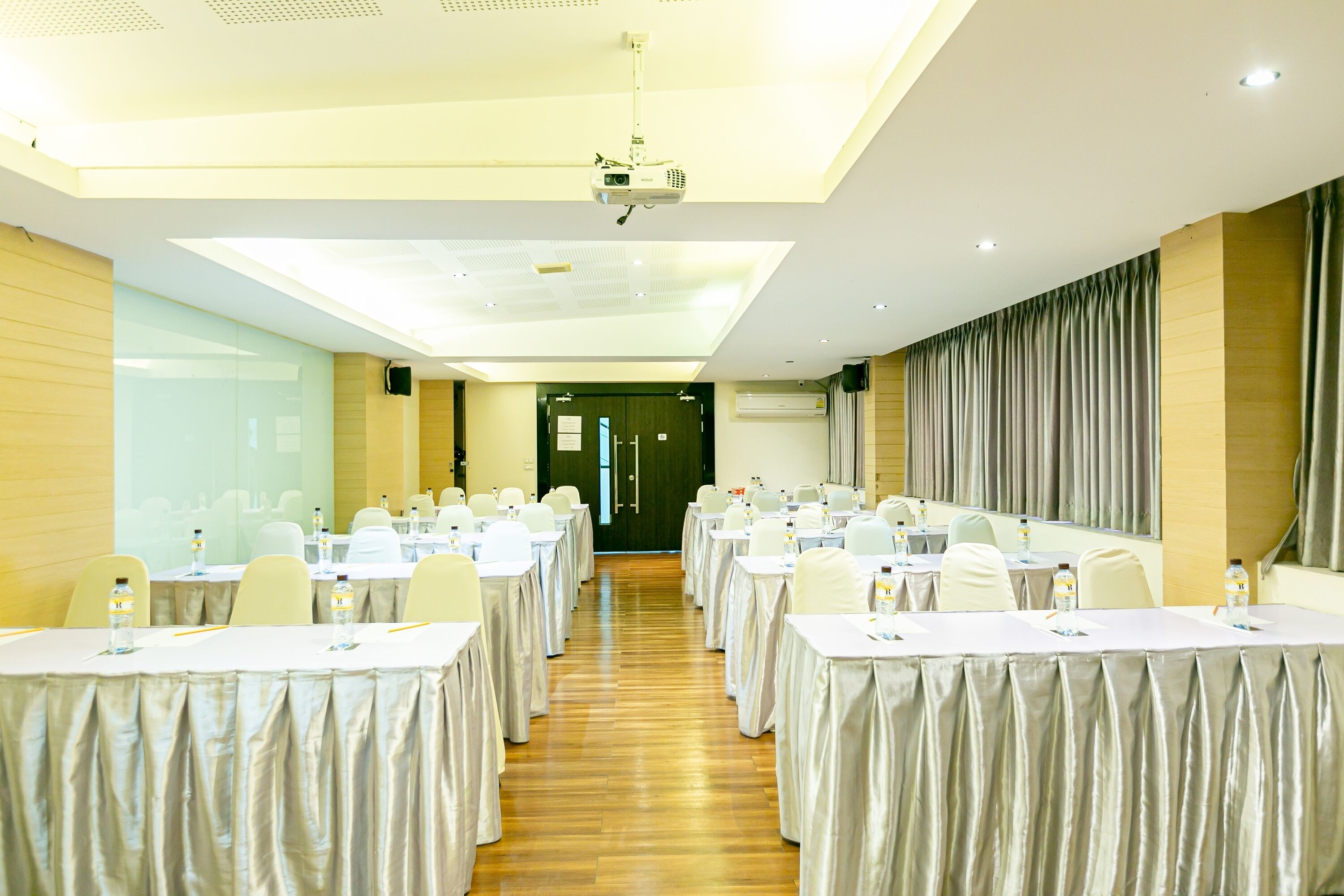 A conference room with long tables, chairs, and a projector.