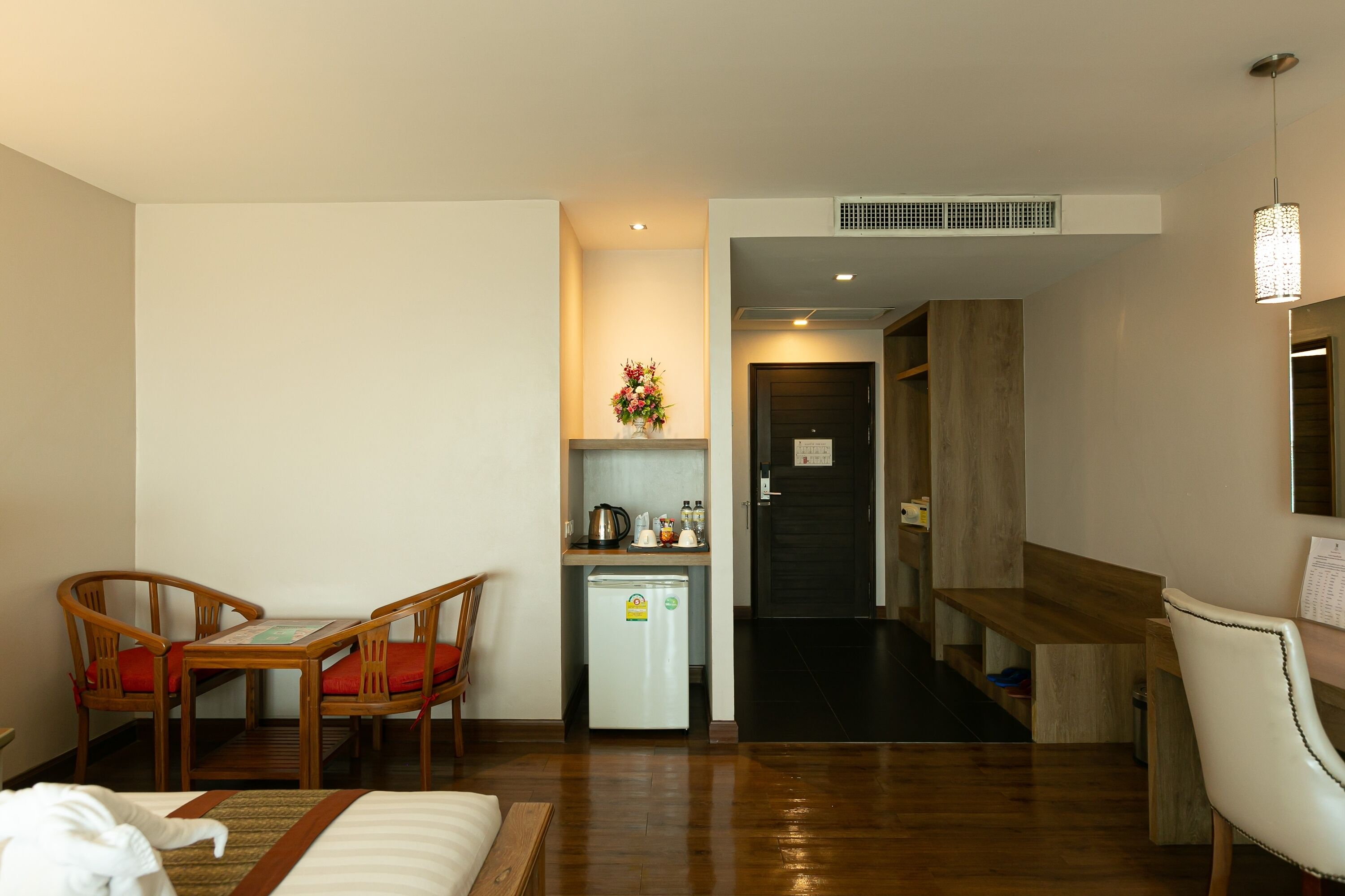 Habitación de hotel con cama, una kitchenette pequeña, zona de comedor con sillas y un banco de madera.