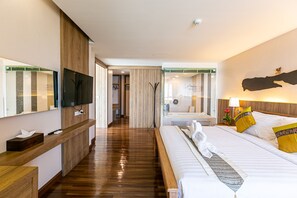 Habitación de hotel con piso de madera, una cama con sábanas blancas, una mesita de noche, un televisor montado en la pared y un espejo.