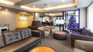A modern hotel lobby with leather sofas, a Christmas tree, and a reception desk. - M Hotel (Kutchan)