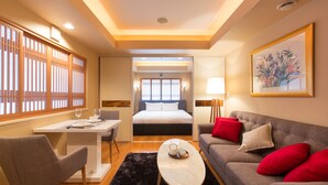 A modern hotel room with a bed, a sofa, a dining table, and a coffee table. - M Hotel (Kutchan)