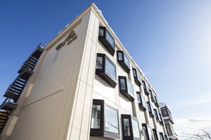 A modern building with a white facade, multiple windows, and a visible fire escape.