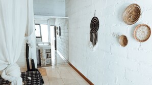 A hallway with a white brick wall, a white sink, and a bench with a patterned cover.
