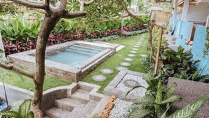 A garden with a pool, stone steps, and various plants.
