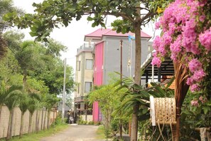 A residential building with a pink vertical stripe, surrounded by lush greenery and flowering plants. - Ramantika Bali House (Jimbaran)