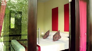 Una habitación con cama, almohadas, una mesita de noche y una ventana con vistas a zonas verdes.