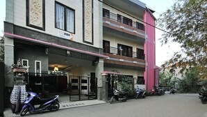 Un edificio de varios pisos con entrada portonada, un letrero y varias motocicletas estacionadas.