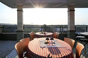An outdoor dining area with checkered tablecloths, round tables, and chairs. - Ramantika Bali House (Jimbaran)