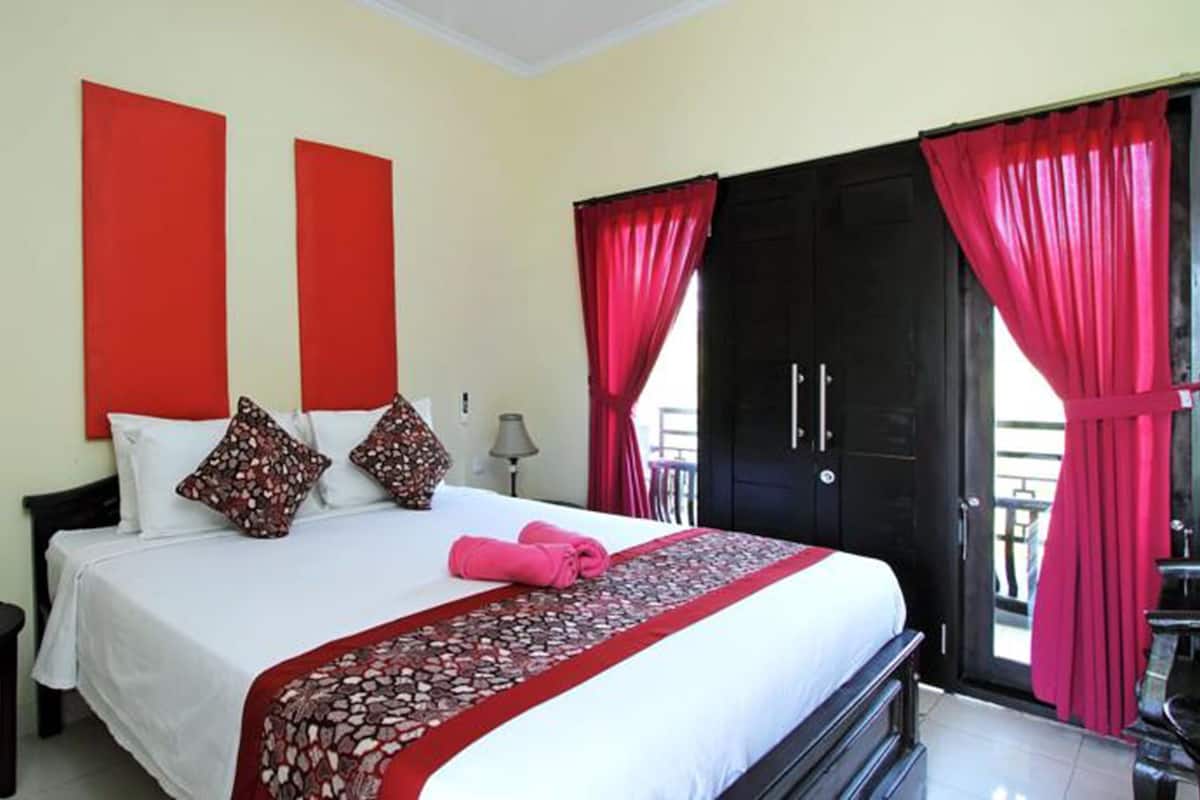 A hotel room with a bed, two nightstands, a red curtain, and a black wardrobe.