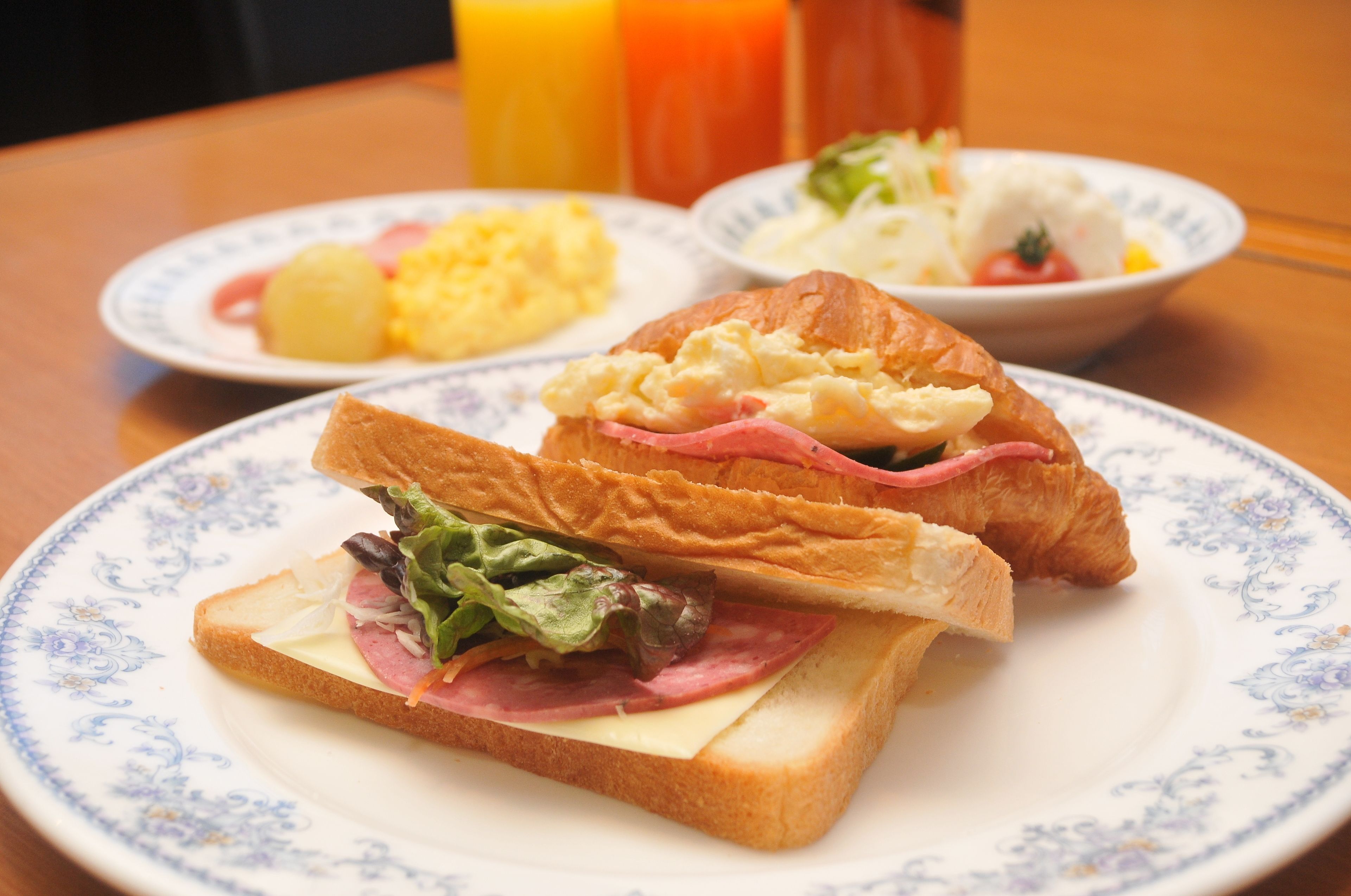 Un plato con un sándwich, un tazón de ensalada y un plato de huevos revueltos.